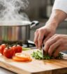 Chef's hands chopping vegetables in a professional kitchen.